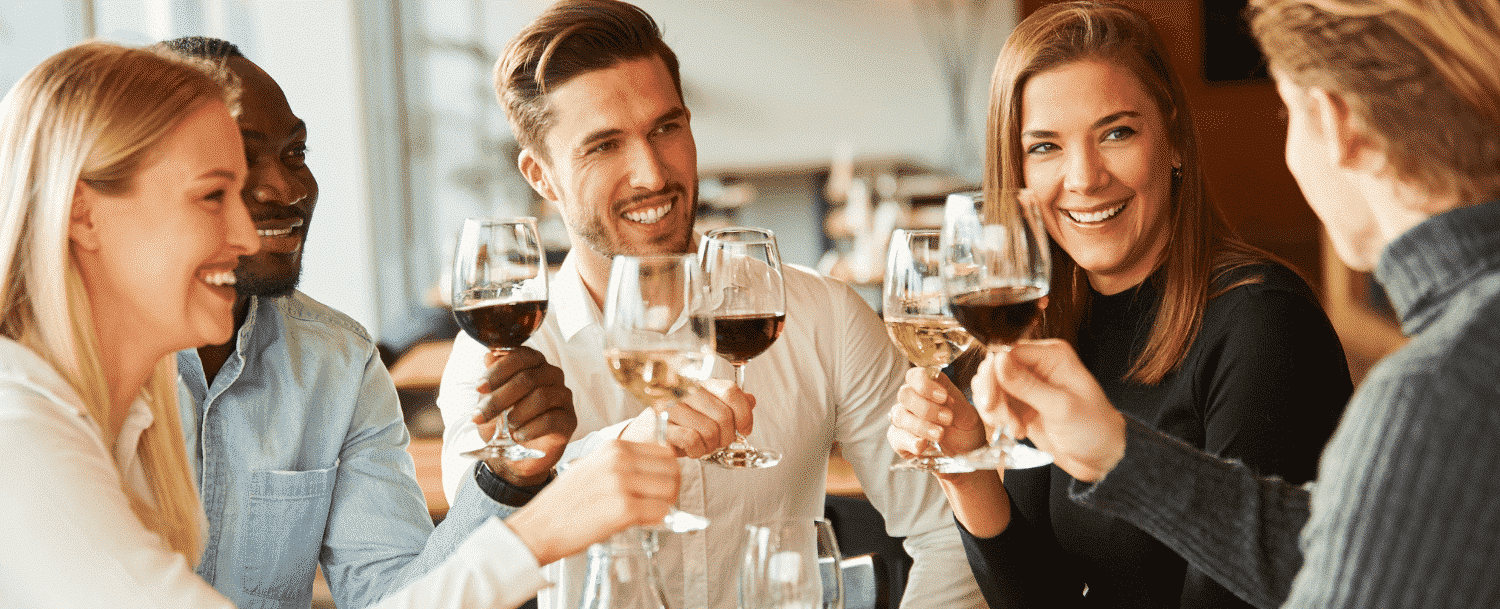 A group of people smiling and toasting with wine glasses.