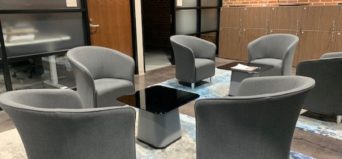 several gray club chairs arounnd a small table in the business discussion space