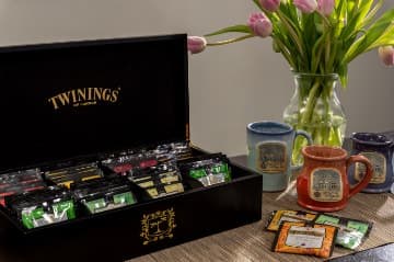 Black wooden box filled with many different colorful packets of tea