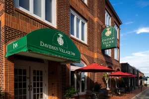 Red brick building housing Davidson Village Inn with signs on side and over entrance door