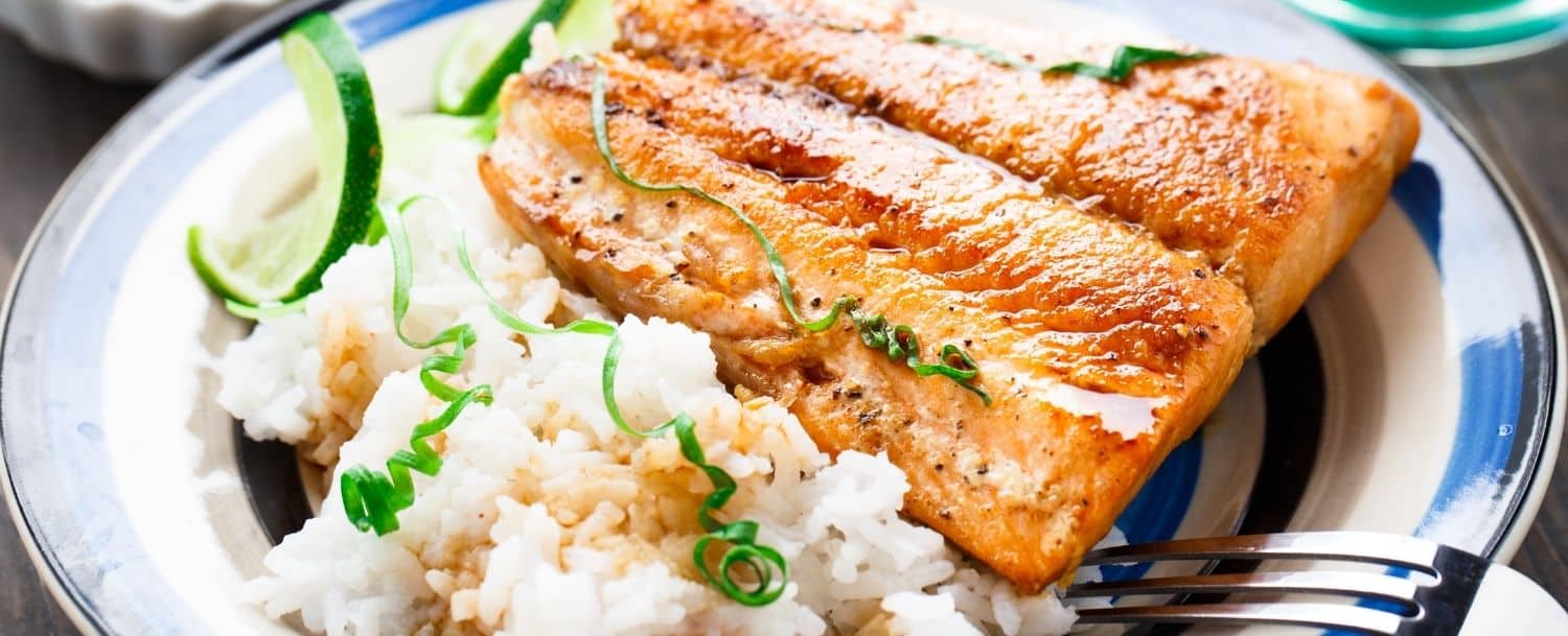 white place of baked salmon, white rice, and slice of lime