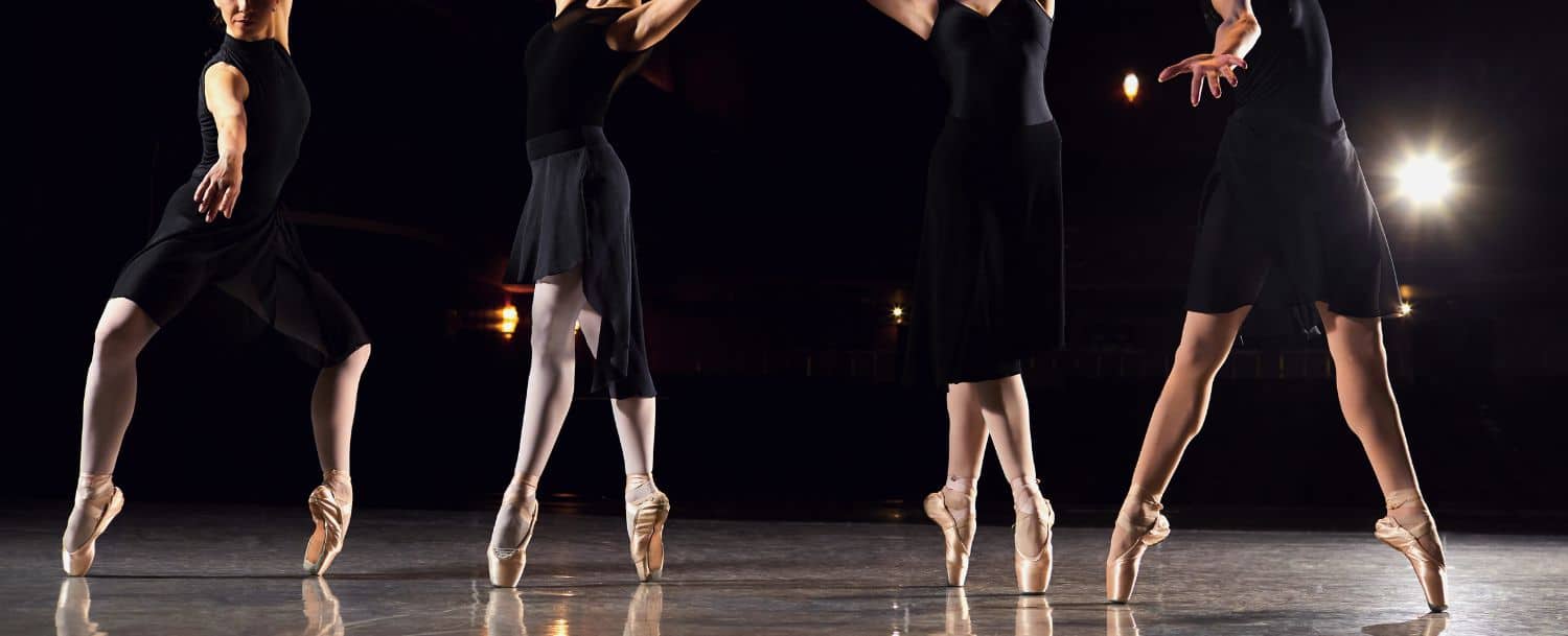 A group of four ballerinas in black on stage
