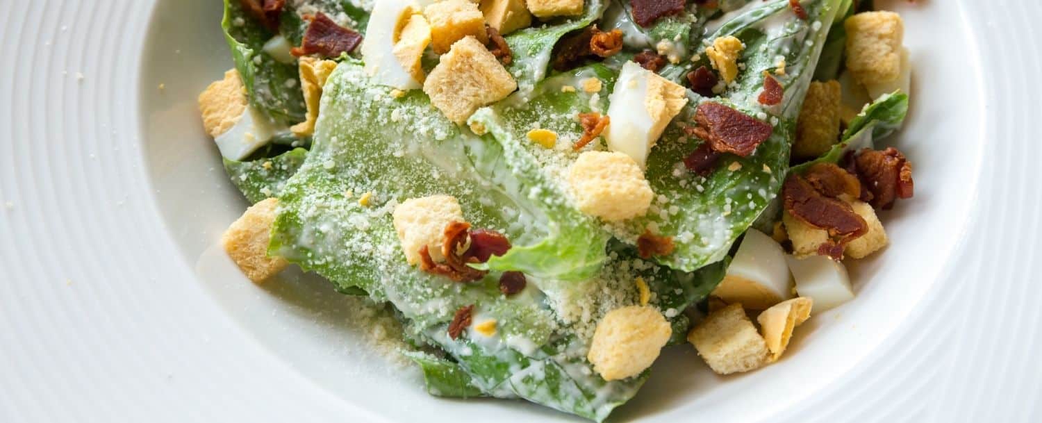 white plate of caesar's salad with croutons and parmesan cheese