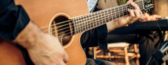 Close-up of a musician playing an acoustic guitar at an outdoor concert in Davidson, NC
