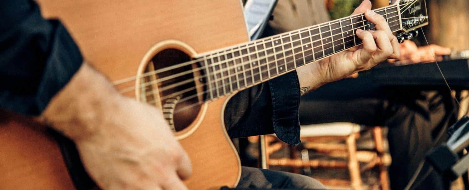 Close-up of a musician playing an acoustic guitar at an outdoor concert in Davidson, NC
