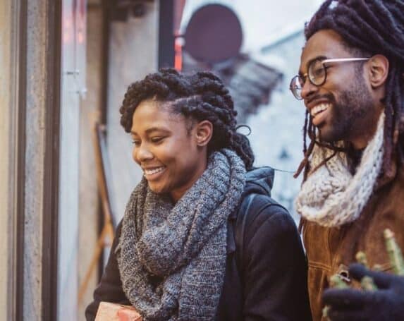 couple smiling while window shopping in the winter