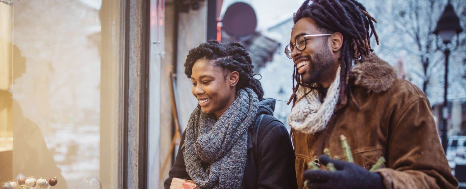 couple smiling while window shopping in the winter