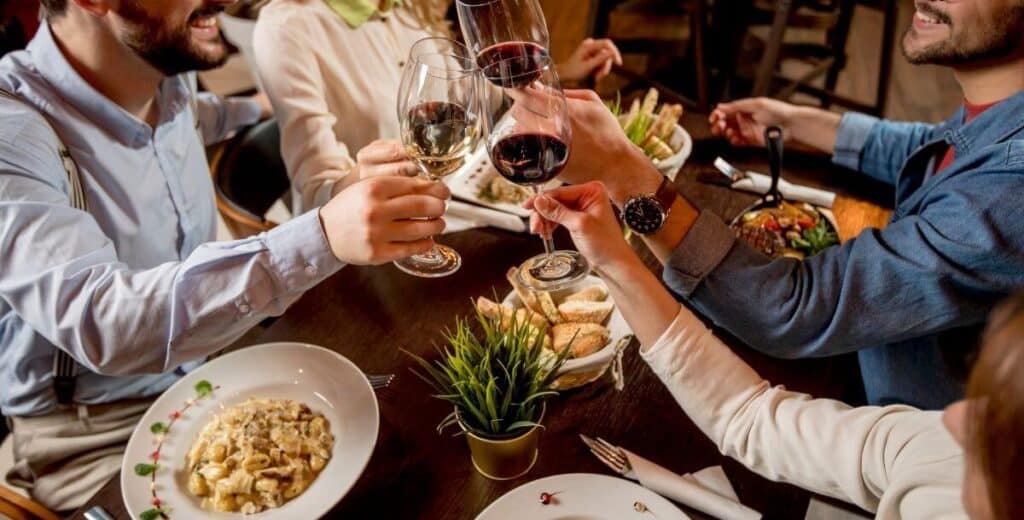 Friends enjoying dinner and raising glasses of wine at a restaurant in downtown Davidson, NC