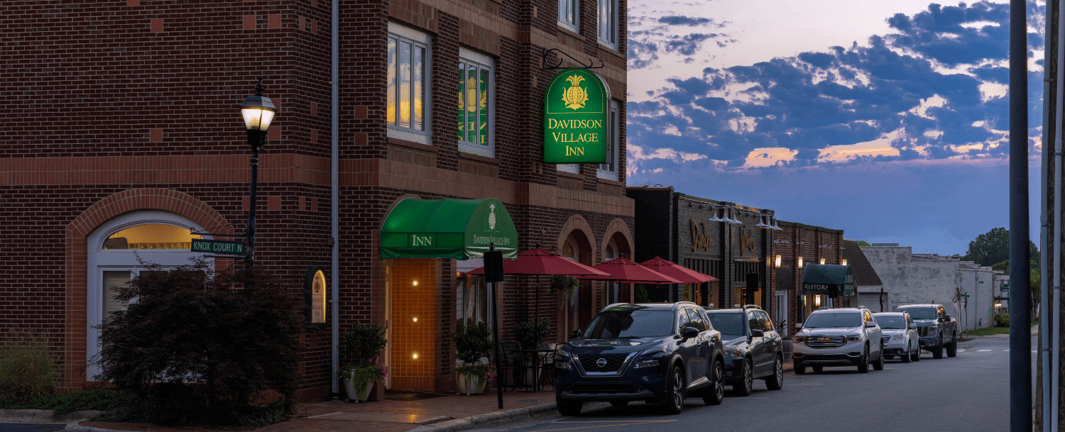 view of front door of davidson village inn and downtown street at twilight 
