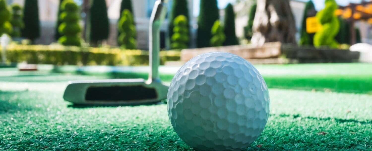 Closeup of golf ball and putter on a mini-golf course