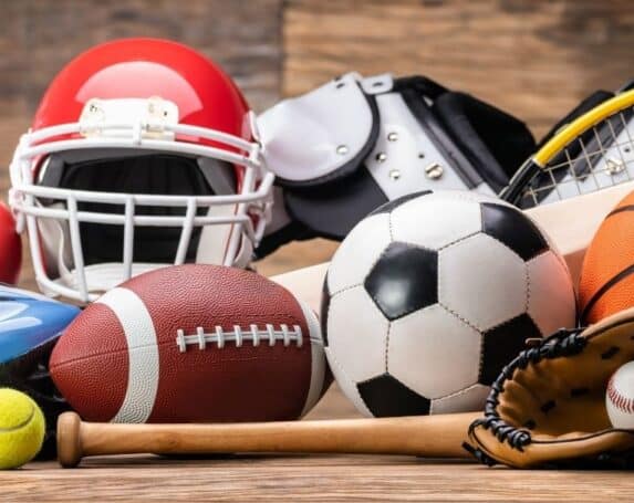 Collection of sports equipment including basketball, football, soccer ball, baseball, tennis racket, and helmet