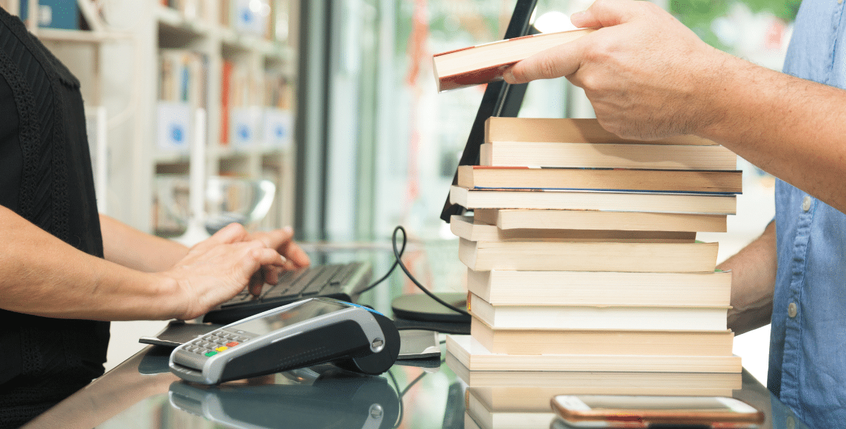 person buying a pile of books at a book store
