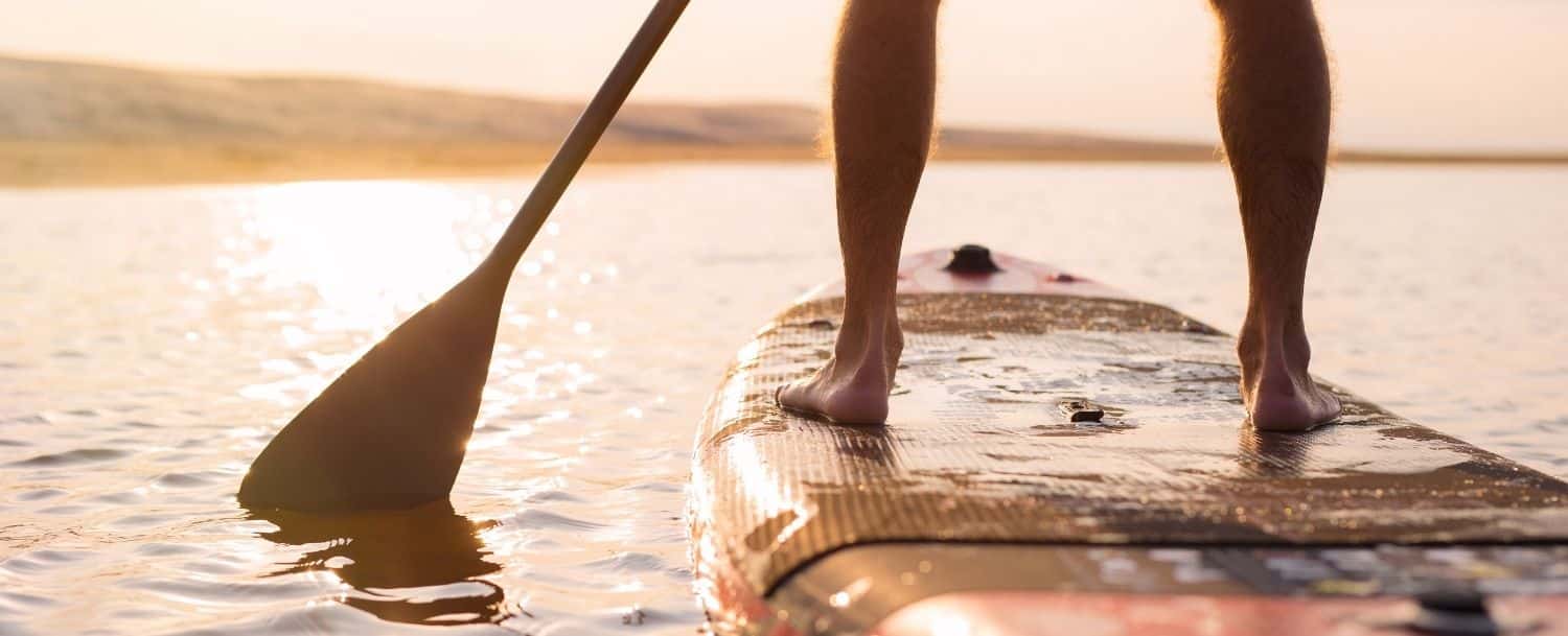 closeup of person paddle boarding at sunset