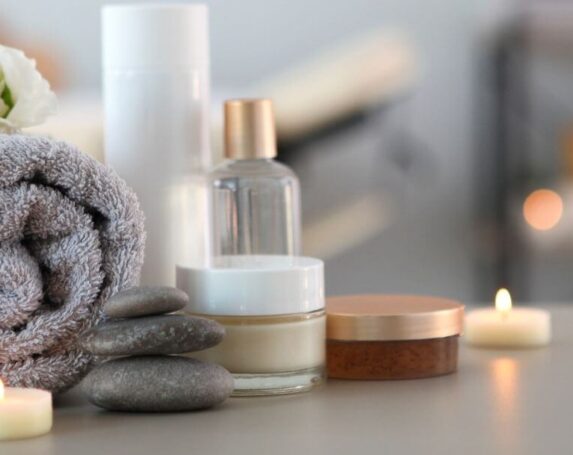 plush towel, lotion, and candles on a table with spa in blurred background