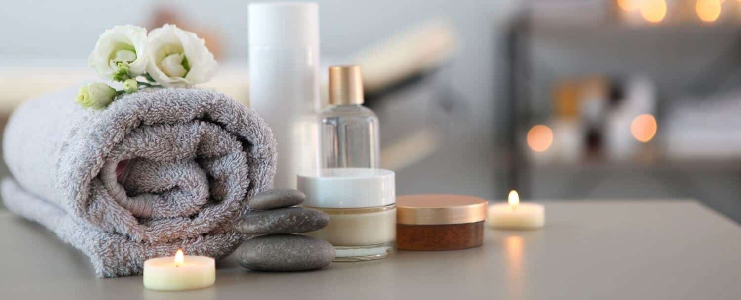 plush towel, lotion, and candles on a table with spa in blurred background