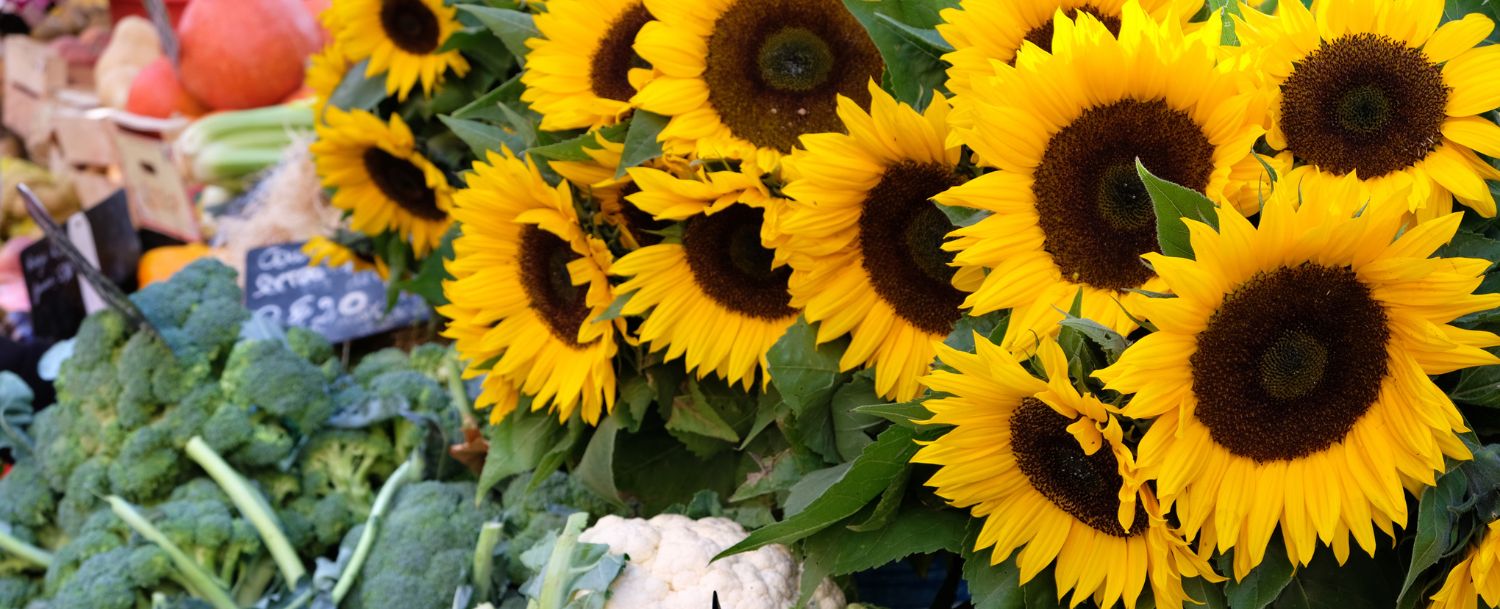 Sunflowers and veggies displayed at a farmers market.