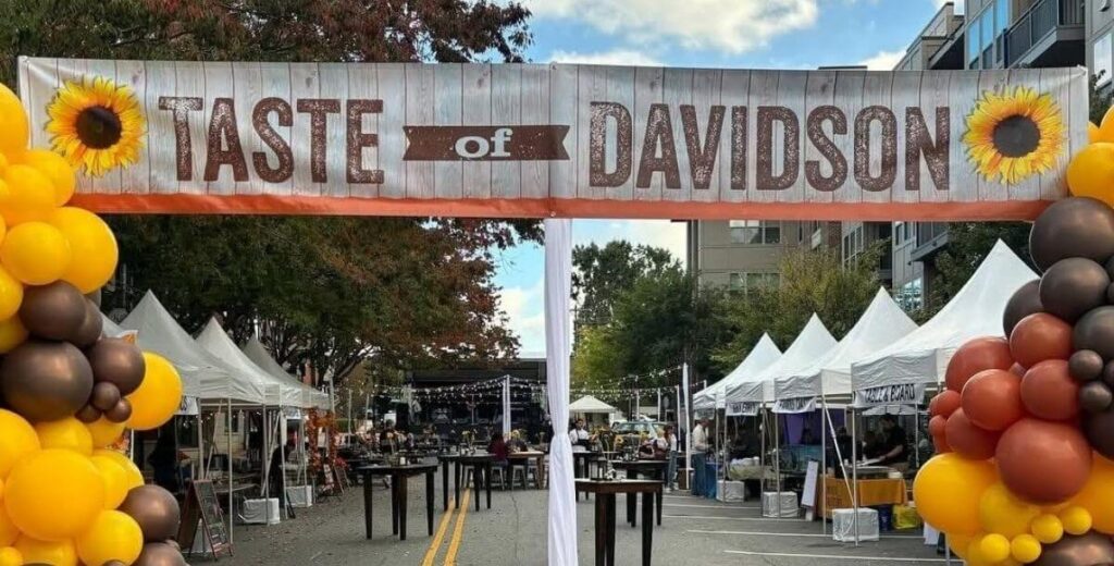 A Taste of Davidson archway with sunflowers and balloons welcomes guests to the fall food festival.