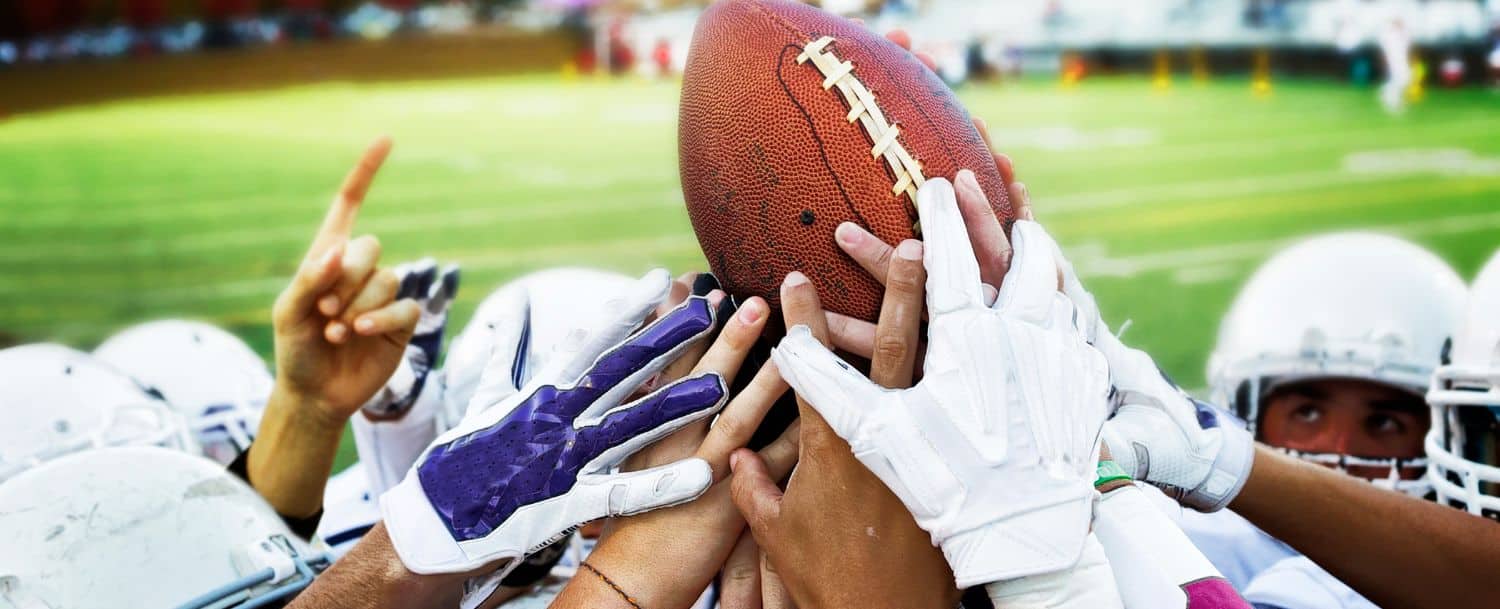 Football players holding up a football