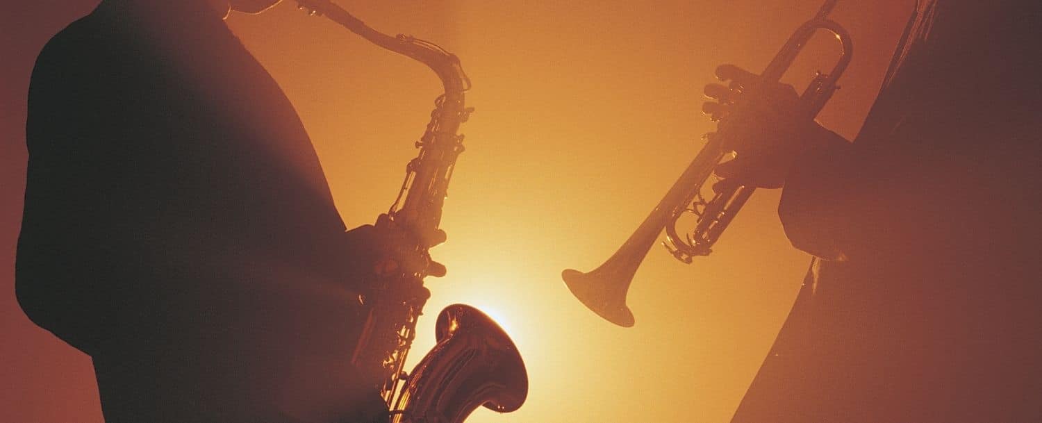 sax and trumpet player silhouettes on a burnt orange-red backdrop