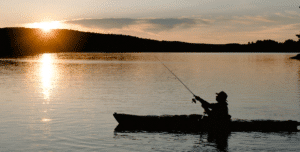Person fishing from a kayak on Lake Norman during sunrise
