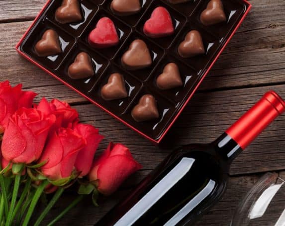 Box of chocolates, red roses and bottle of red wine