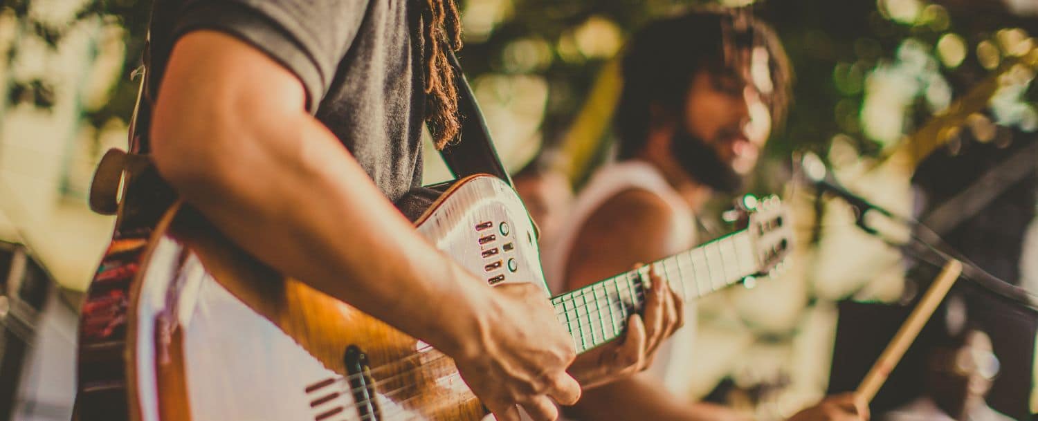Two people playing guitars outside 