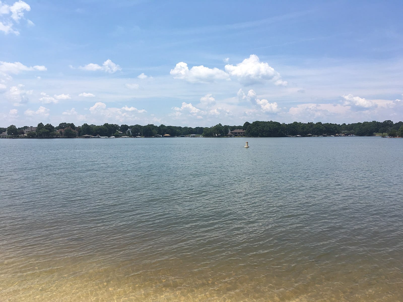 Scenic view of Lake Norman surrounded by trees and houses and blue skies