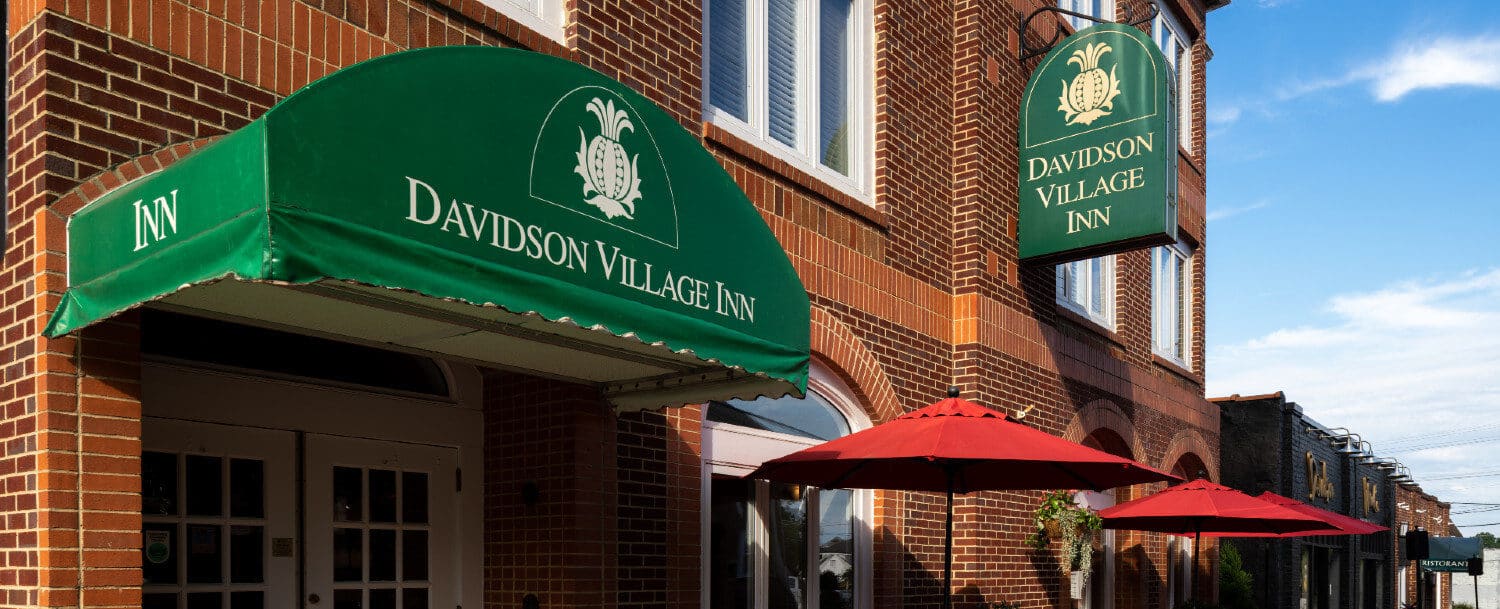 Red brick building housing Davidson Village Inn with signs on side and over entrance door