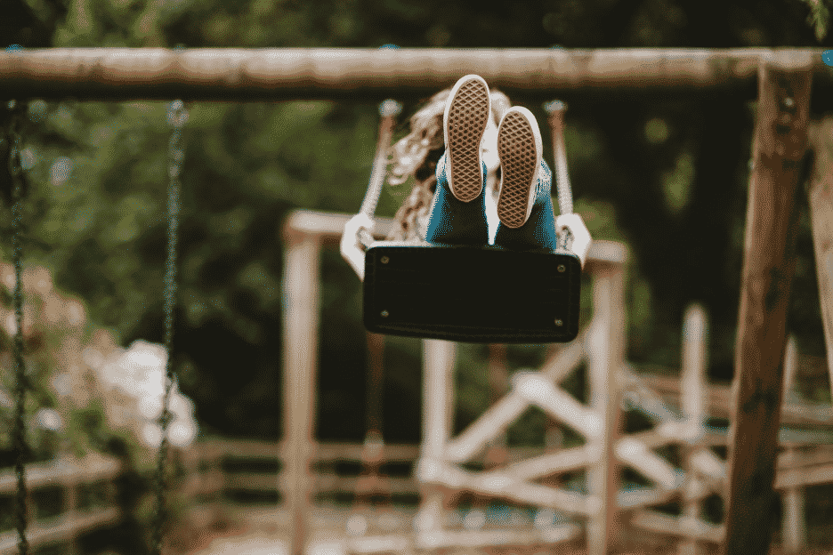 Girl swinging on an outdoor wooden swingset