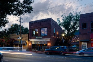 Red brick building for Kindred Restaurant, cars parked along street in front