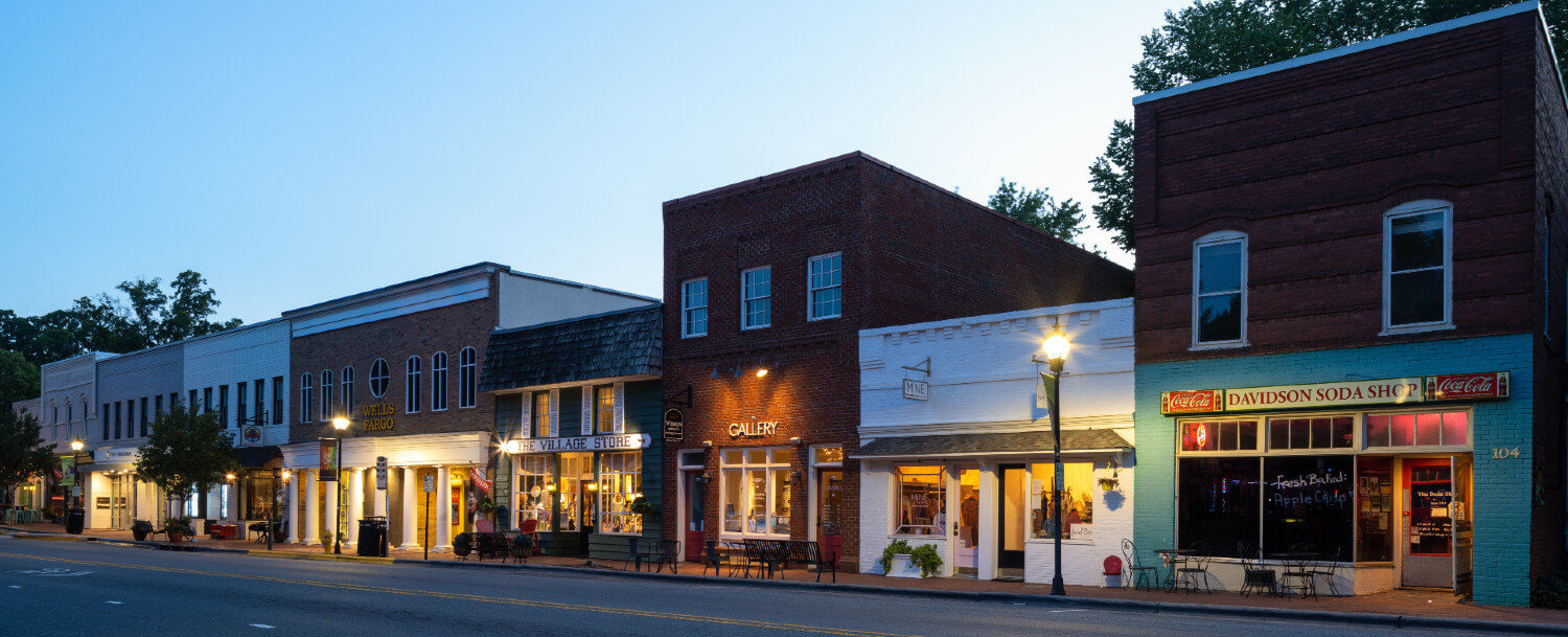 Stores along main street lit with lamps and individual lights on stores in Davidson, NC