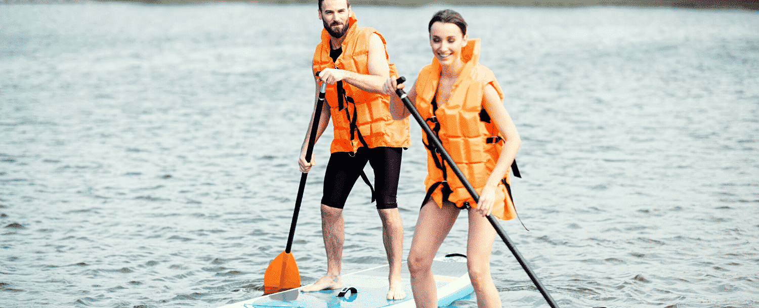 Couple paddle boarding on a lake.