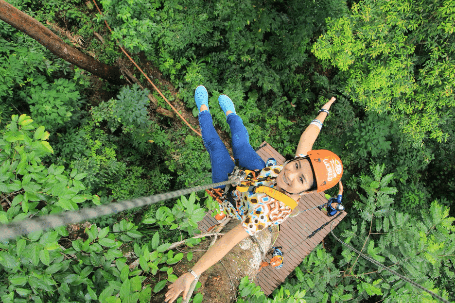 Girl ziplining through the lush green trees